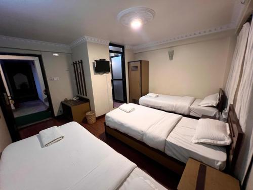 a hotel room with three beds and a television at Taleju Grand Hotel in Bhaktapur