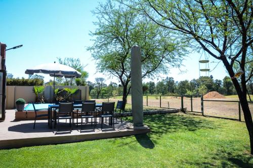 a patio with a table and chairs and an umbrella at 2916 on Egret - Parys Country and Golf Estate - Loadshedding friendly in Parys