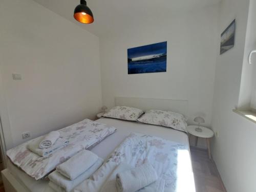 a white bedroom with two beds and a table at Apartment Primosten Adiomare in Primo&scaron;ten