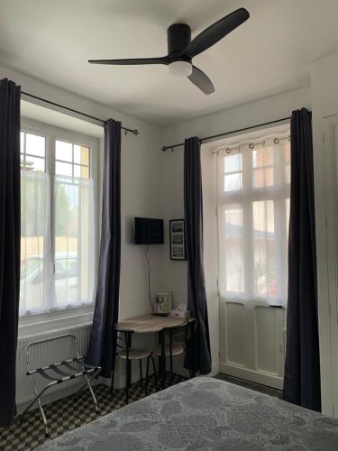 a bedroom with a ceiling fan and a table and windows at Chez Chris in Cour-Cheverny