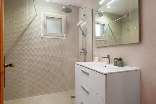 a bathroom with a sink and a shower with a mirror at Villa Canta in Playa de Muro