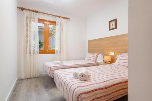 two twin beds in a room with a window at Villa Canta in Playa de Muro