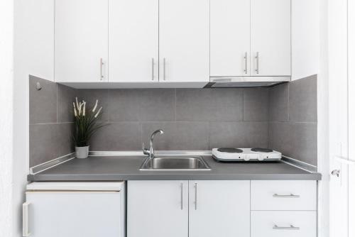 a kitchen with white cabinets and a sink at Valasi Studios in Skála Foúrkas