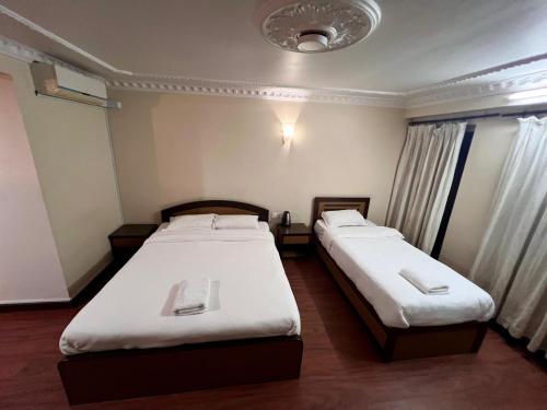 two beds in a small room with white sheets at Taleju Grand Hotel in Bhaktapur
