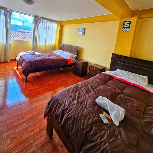 a bedroom with two beds and a large window at Pachamama Hostel in Cusco
