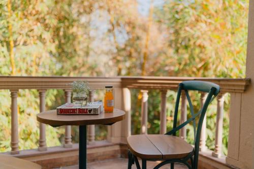 a table and chair on a balcony with a bottle of orange juice at Karma Chalets in Gurgaon