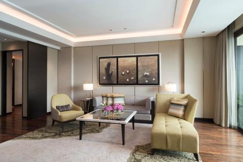 a living room with a couch and a table and chairs at Siam Kempinski Hotel Bangkok in Bangkok