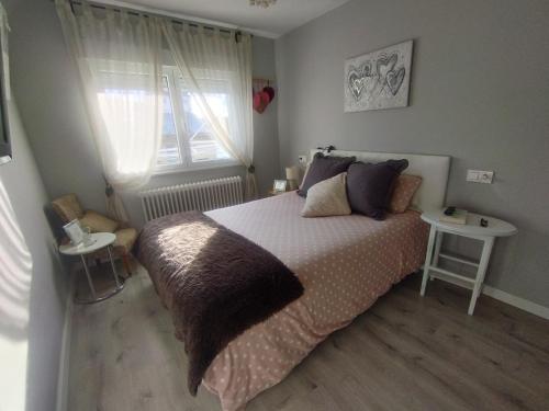 Un dormitorio con una cama grande y una ventana en Ático 4 personas con terraza amueblada y vistas. en Oviedo