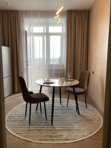 ein Esszimmer mit einem Tisch und Stühlen auf einem Teppich in der Unterkunft Alpamys Premium центр города in Qostanai