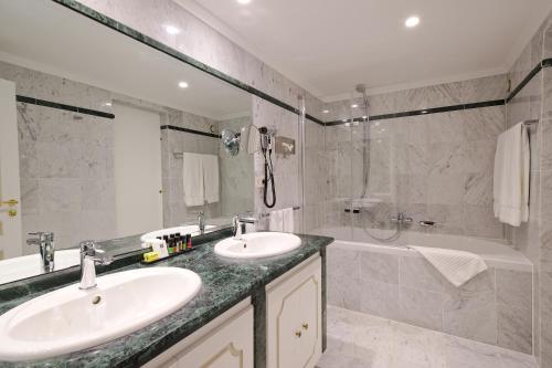 a bathroom with two sinks and a shower and a tub at Hotel Manos Premier in Brussels