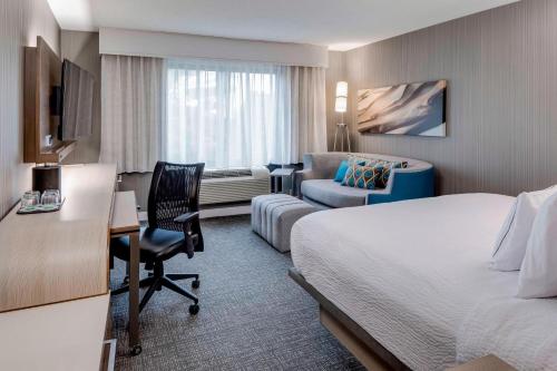 a hotel room with a bed and a desk and a chair at Courtyard by Marriott Portsmouth in Portsmouth