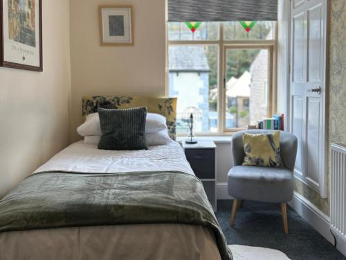 a bedroom with a bed and a chair and a window at Beautiful 2-Bed Cottage in Heysham Village in Heysham
