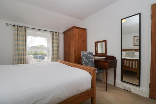 een slaapkamer met een bed, een bureau en een spiegel bij Incline Cottage in Portreath