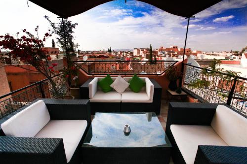 balcón con sofás, mesa y sombrilla en Riad El Grably en Marrakech