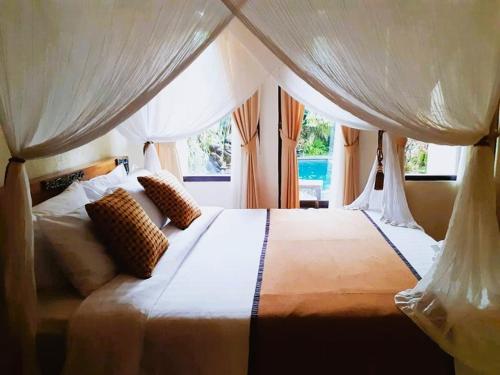 een slaapkamer met een groot wit bed en een raam bij Merta House Jasan Village in Tegalalang
