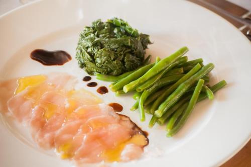 a plate of food with salmon green beans and vegetables at The Charming Lonno Lodge Watamu in Watamu