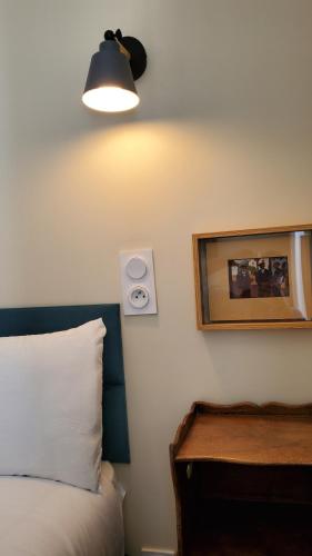a bedroom with a bed and a light on the wall at Grand Hôtel de la Poste in Saint-Jean-de-Luz
