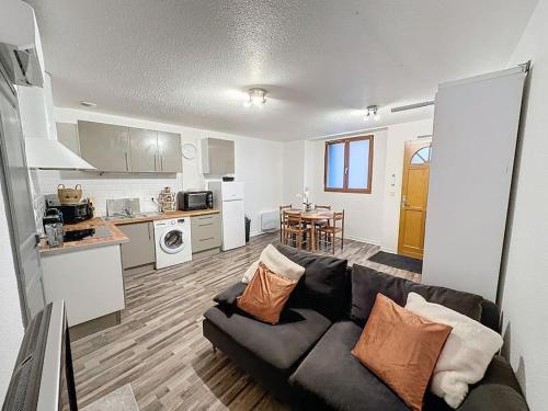 un salon avec un canapé noir et une cuisine dans l'établissement Séjour tout confort à10 minutes du Sanctuaire Lourdes, à Lourdes