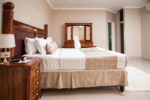 a bedroom with a large bed and a wooden dresser at Fatmols City Hotel in Ndola