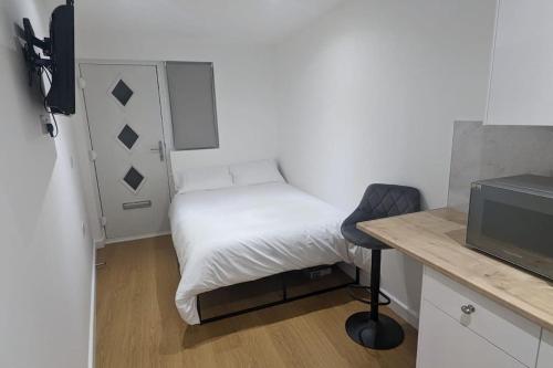 um pequeno quarto com uma cama e uma secretária com uma televisão em Southend Airport Ground Floor Studio, with parking em Southend-on-Sea