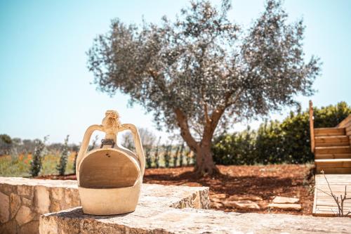 a jug sitting on a stone wall with a tree at Trulli Beauty Romantic ALCOVA con piscina in Locorotondo