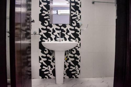 a bathroom with a sink and a black and white wall at Budget Friendly 3 BHK + Prime Location in Faridabad