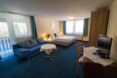 a living room with a blue couch and a bed at Gasthof Braun in Schmallenberg
