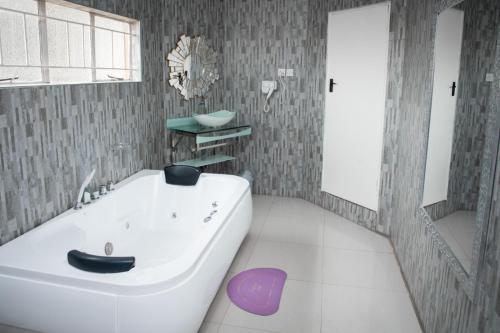 W łazience znajduje się duża, biała wanna i lustro. w obiekcie Fatmols City Hotel w Ndola