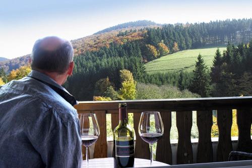 a man sitting at a table with two glasses of wine at Gasthof Braun in Schmallenberg