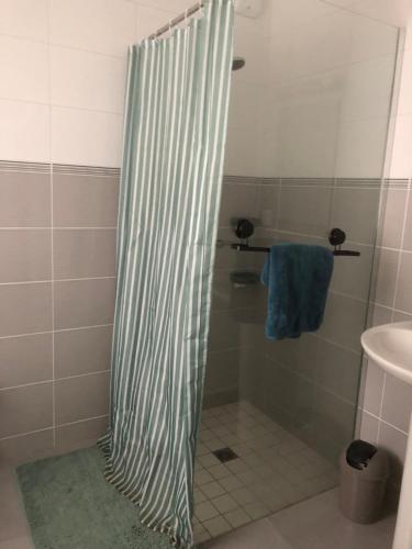 La salle de bains est pourvue d'une douche avec rideau de douche à rayures. dans l'établissement Autret, à Guipavas
