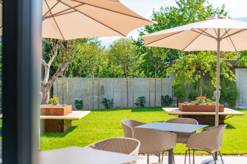 a patio with tables and chairs and an umbrella at Hotel Garni Vinea Montis in Termeno