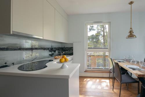 a white kitchen with a sink and a dining table at Apartamenty In Mestwina 37 Jurata in Jurata