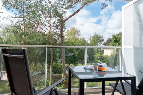 a black table and a chair on a balcony with a window at Apartamenty In Mestwina 37 Jurata in Jurata