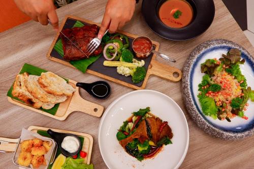 a wooden table with plates of food on it at PARKROYAL Suites Bangkok in Bangkok
