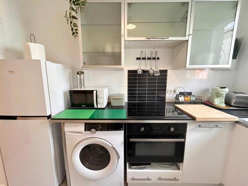 eine Küche mit einer Waschmaschine und einer Mikrowelle in der Unterkunft Appart chaleureux et calme près de PARIS et MÉTRO in Asnières-sur-Seine