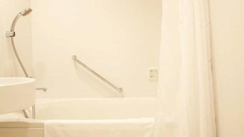 a white bathroom with a tub and a shower curtain at Shin-Osaka Station Hotel in Osaka