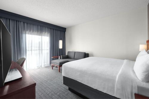 a hotel room with a bed and a chair at Courtyard St. Louis Creve Coeur in Creve Coeur
