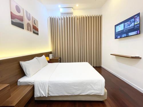 een hotelkamer met een wit bed en een televisie bij Ngọc Toàn Hotel in Dong Hoi