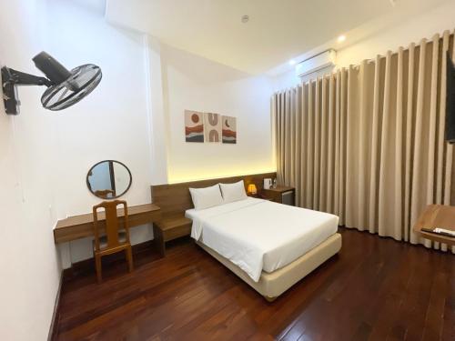 een slaapkamer met een bed en een bureau met een spiegel bij Ngọc Toàn Hotel in Dong Hoi