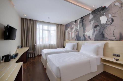 a hotel room with two beds and a painting on the wall at Four Star by Trans Hotel in Sanur