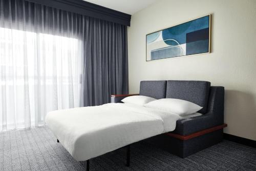 a bed and a chair in a hotel room at Courtyard St. Louis Westport Plaza in Maryland Heights