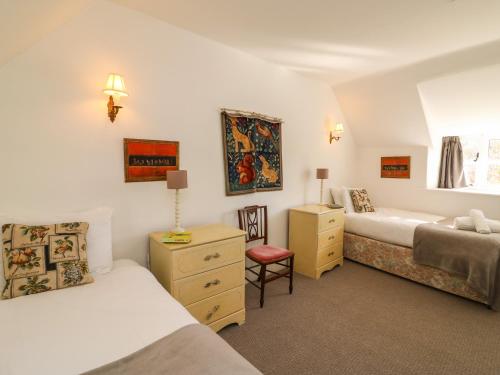 Un dormitorio con 2 camas y una silla. en Lychgate Cottage en Osmington