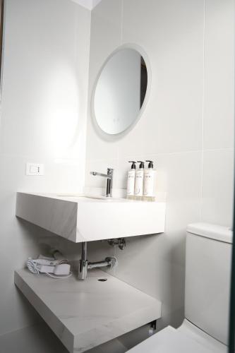 a white bathroom with a sink and a mirror at Doko Hotel in Vlorë