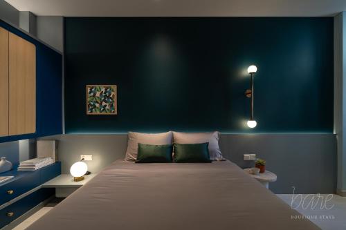 a bedroom with a large bed with a blue wall at Bare Hyphen - Bare Boutique Stays in Ho Chi Minh City