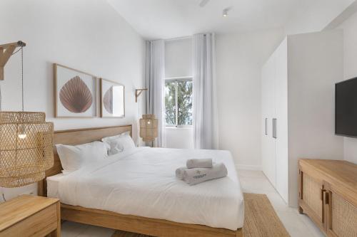 Dormitorio blanco con cama blanca y TV en Ocean Grand Gaube en Grand Gaube
