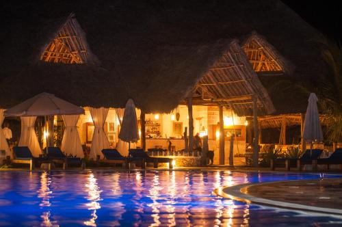 a resort swimming pool with umbrellas and chairs and a pool at The Charming Lonno Lodge Watamu in Watamu