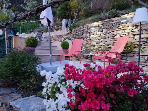 two chairs and flowers in front of a stone wall at Private Romantic Wellness Lake View Retreat- Whirlpool Hammam Spa e Piscina panoramica in Maccagno con Pino e Veddasca