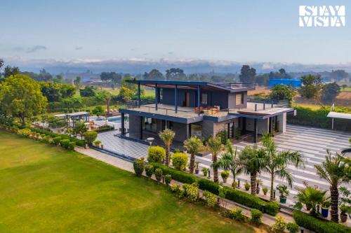 una vista aérea de una casa con jardín en StayVista's Hampton Acres - Outdoor Pool, Vast Lawn & Terrace, en Dhauj
