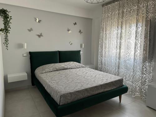 a bedroom with a green bed and a window at B&B Chiedi la Luna in San Vito lo Capo