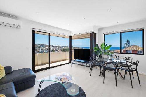 un soggiorno con divano, tavolo e sedie di Dream View - Steps from the Beach & Secure Parking a Sydney